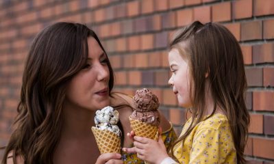 Mom and daughter eating ice cream outdoors with a brick wall in the background