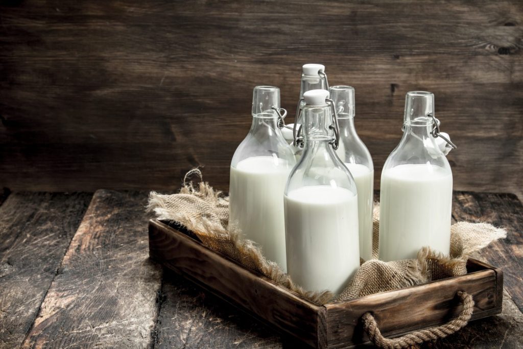 Bottles with fresh milk in a box. On a wooden background.