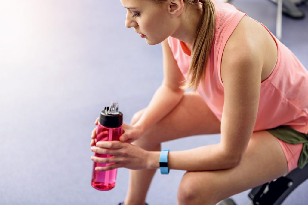 Thoughtful woman tasting beverage in fitness center