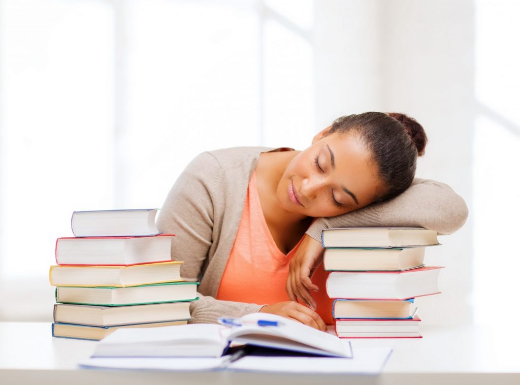 education and business concept - tired student with pile of books and notes studying indoors