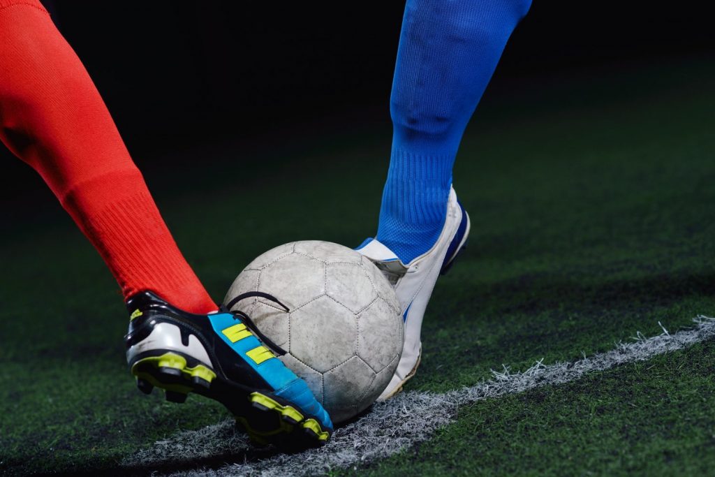 soccer player doing kick with ball on football stadium field isolated on black background