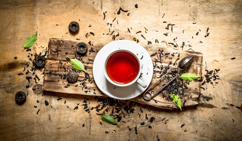Tea with leaves and cinnamon. On wooden background.