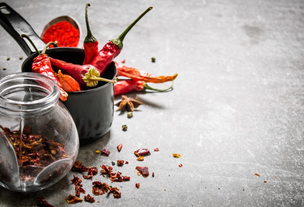 Dried peppers in a jar. On a stone background. Free space for text .