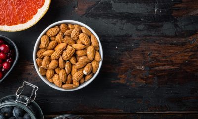 Almonds nuts with healthy food, top view on dark wooden background, with copy space