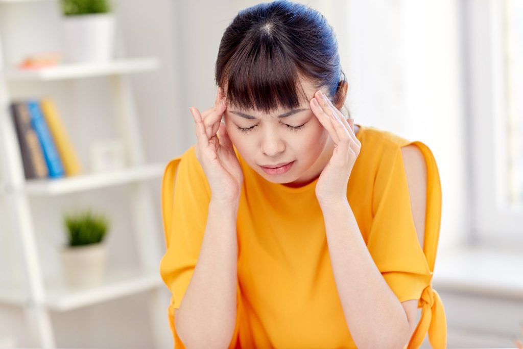 people, healthcare, stress and problem concept - unhappy asian young woman suffering from headache at home